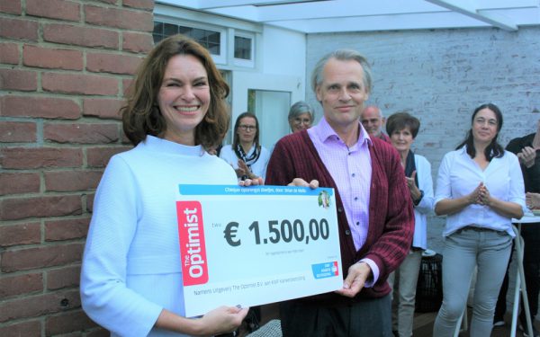 Roland Pluut van Uitgeverij The Optimist reikt een cheque uit ten behoeve van KWF Kankerbestrijding.