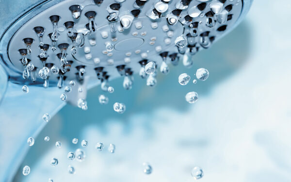 Closeup,Of,A,Shower,Head,With,Sprinkling,Water,,Blue,Toned