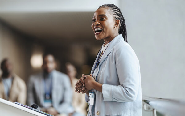 Professional,African,Woman,With,A,Radiant,Smile,Engages,Attendees,As